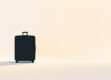A minimalist silhouette of a suitcase against a gradient background, symbolizing travel.