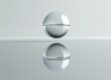 A metallic sphere floating above a reflective surface, casting a distorted mirror image.