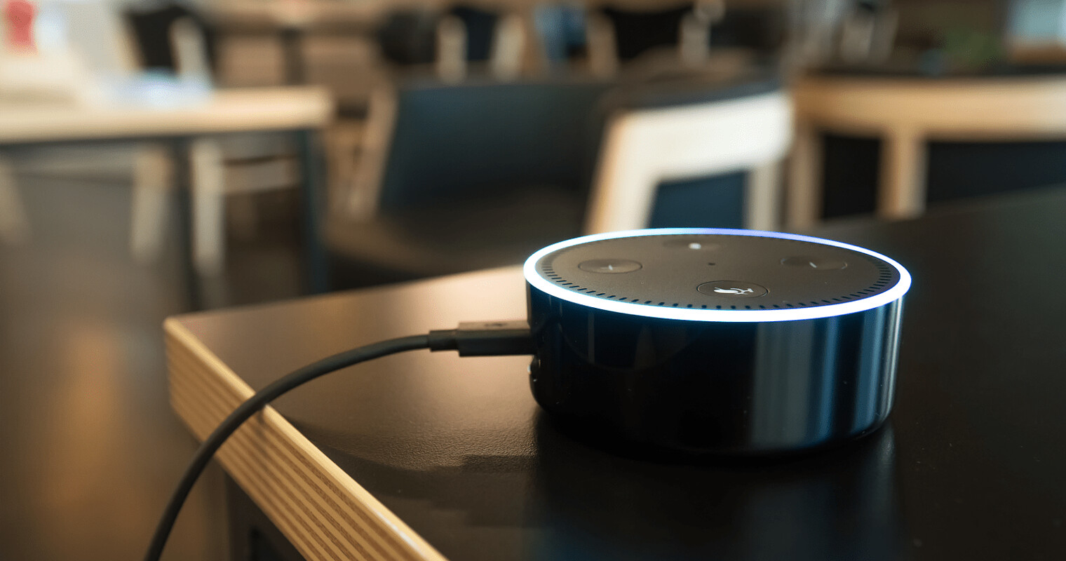 Digital assistant device with black design and illuminated ring.