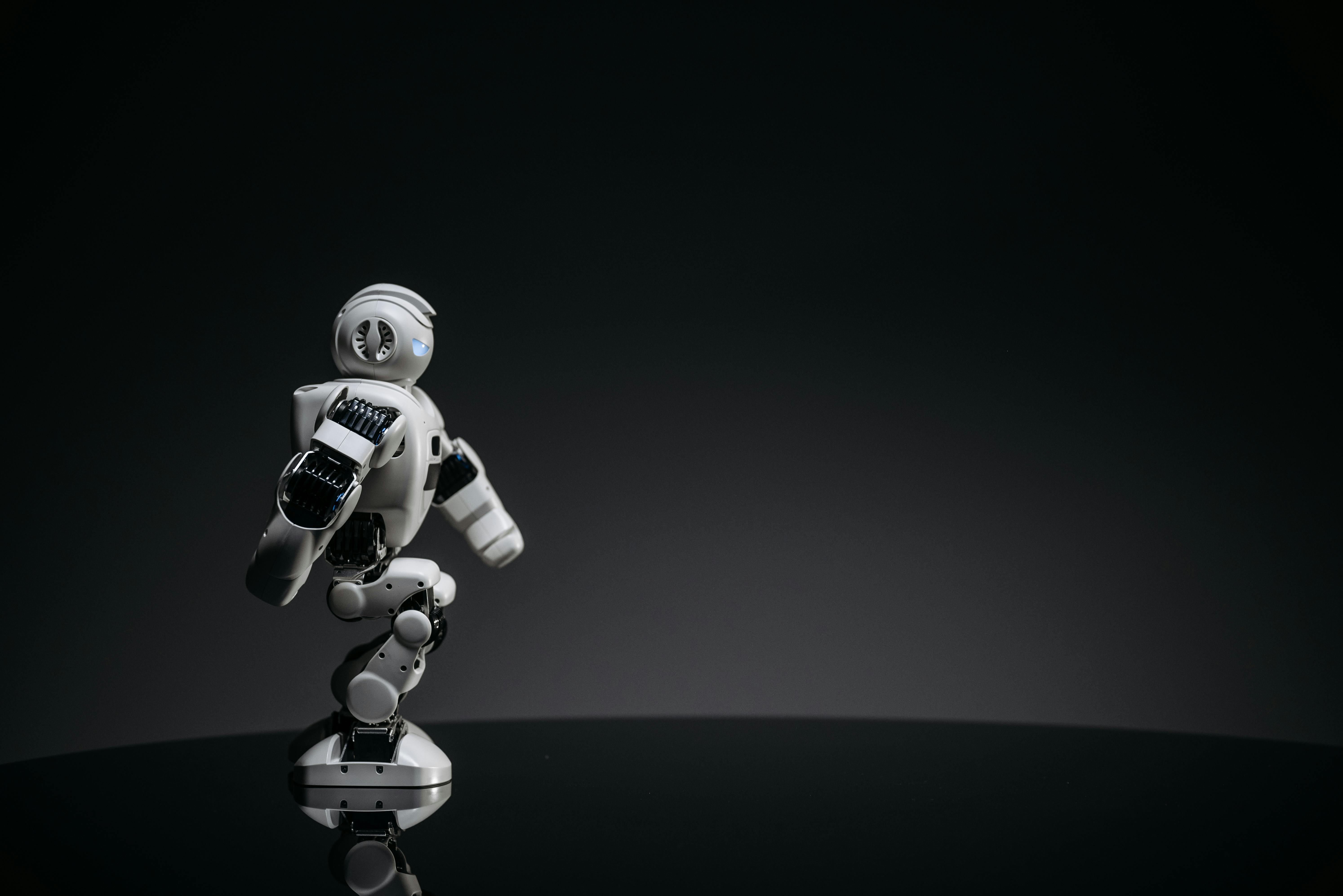 A small humanoid robot with articulated limbs in a dark setting