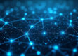 Aerial view of a complex network of glowing, interconnected nodes in blue and white tones against a dark background.