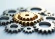 Professional photograph of interlocking gears with a golden gear in the center.